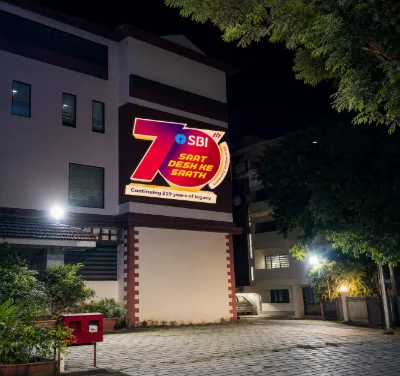 Red and yellow SBI anniversary graphic projected onto a building facade at night
