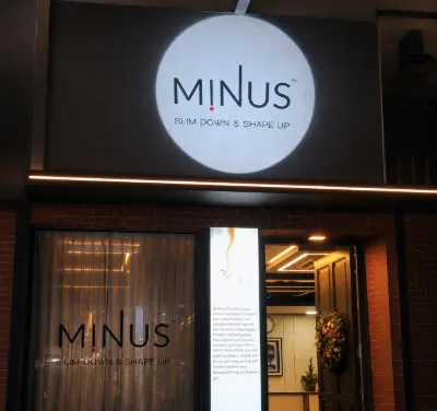 White MINUS logo projected above a warmly lit storefront entrance at night